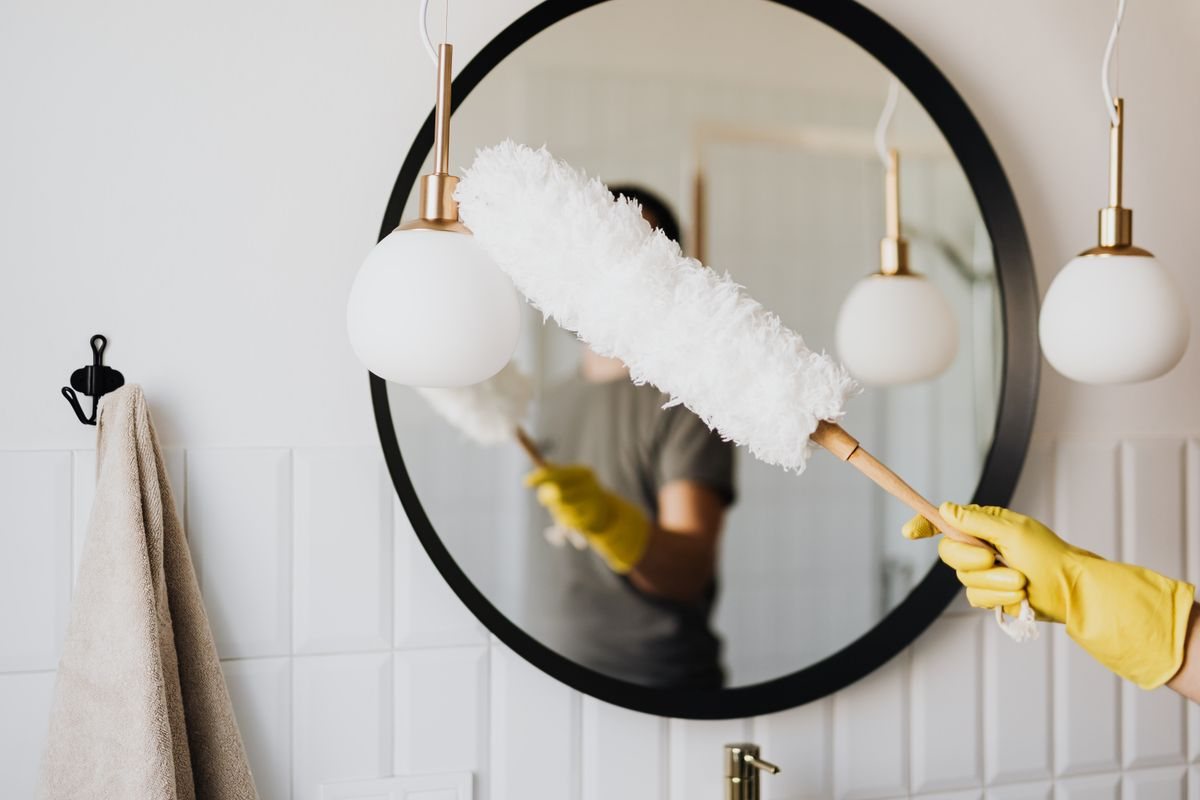 Un geste de dépoussiérage dans une salle de bain soignée